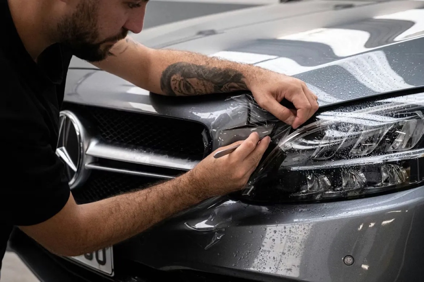Technician working on the front end of a dark car